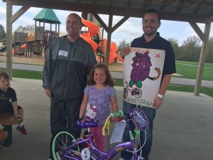 Past poster contest winner with her new prize bike standing with MFF CEO and principal