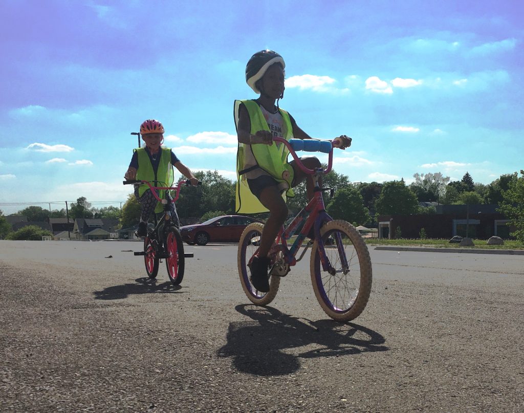 Two students in safety vests on bikes participating in Bike Club held by the Crim Fitness Foundation