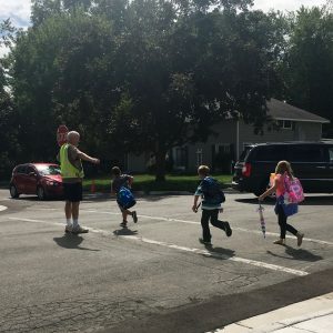 A man is guiding kids to cross the street