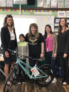 Bunch of girls with a kid is standing next to a bike 