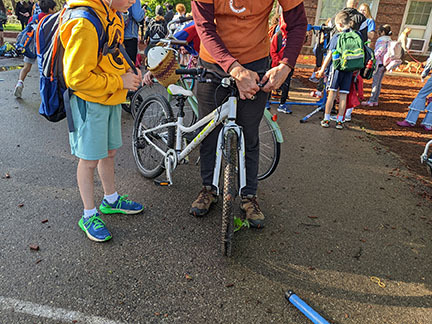 And adult helping a child getting his bike ready to ride.