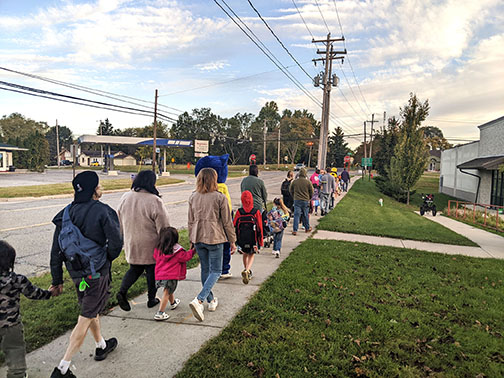 Group of families walking down a sidewalk on the way to school