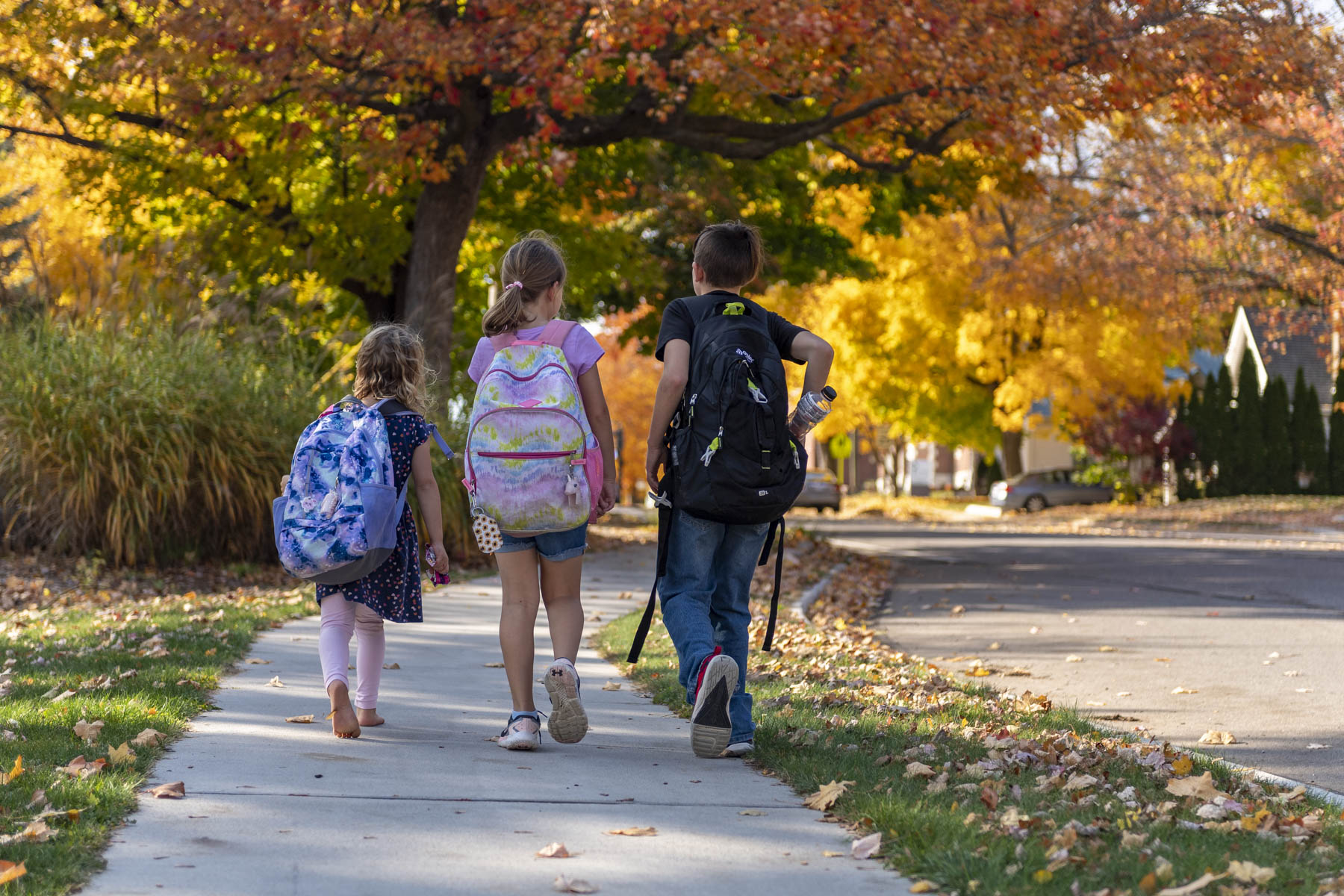 Three kids are using new sidewalk after improvement