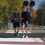 Two smiling children cross railroad with the new rubber flangeway and concrete ADA approaches.