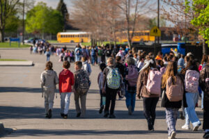 Imlay City Students walk toward school with buses in the background as part of Walk and Roll to School Day event.