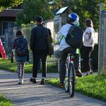 Students walk and bike along a sidewalk to the school entrance. 