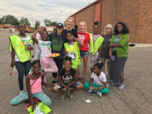 Bike club students in high-vis vest and instructors stand together outside a school.