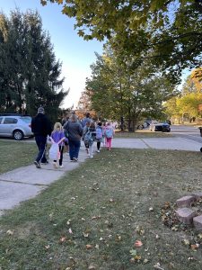 students walk on sidewalk with trees in the background.