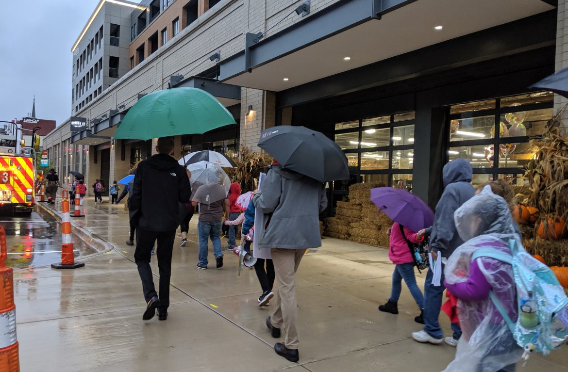 Walk to School Event with pedestrians using umbrellas and wearing rain ponchos