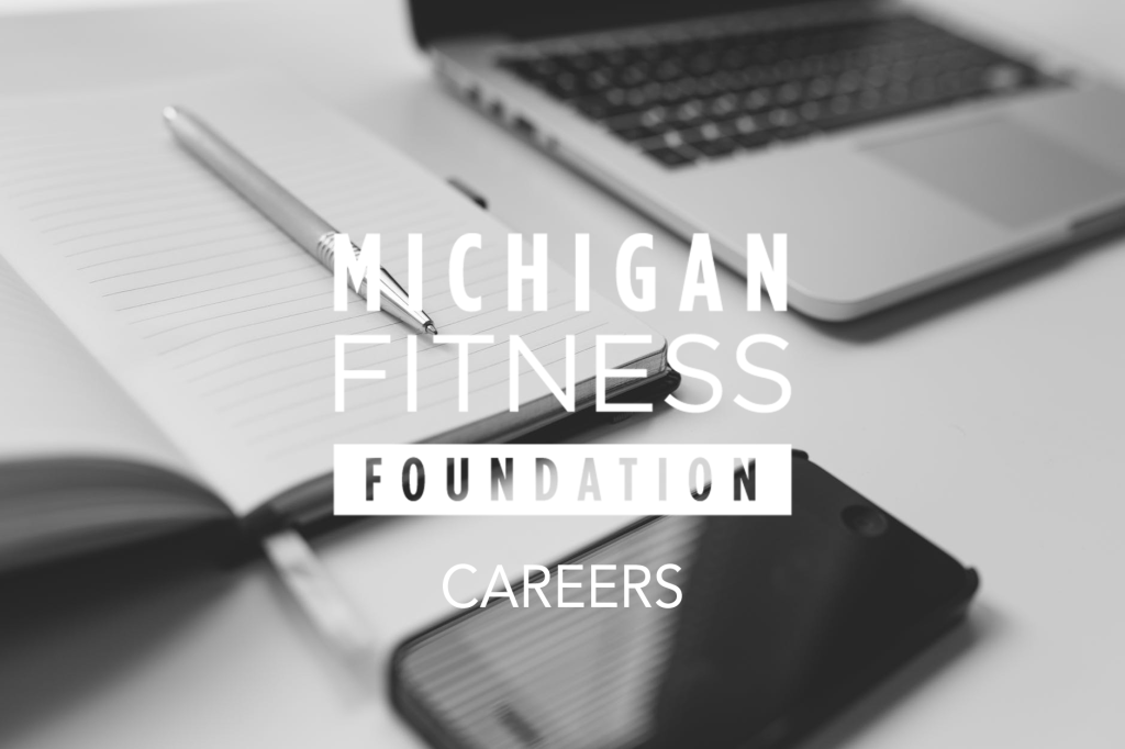 black and white image of a laptop, cellphone and an opened notebook with pen with the Michigan Fitness Foundation Logo and the work Careers in caps centered over the image.