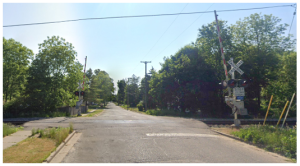 View of the railroad crossing at Henry Street before the SRTS project. Shows a sidewalk on the north side of the road and no walking facility on the south side of the road.