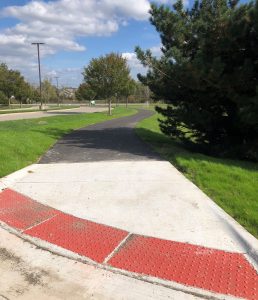 Concrete ADA approach with truncated domes leading to an asphalt multi use path along the entry of Novi Woods School.