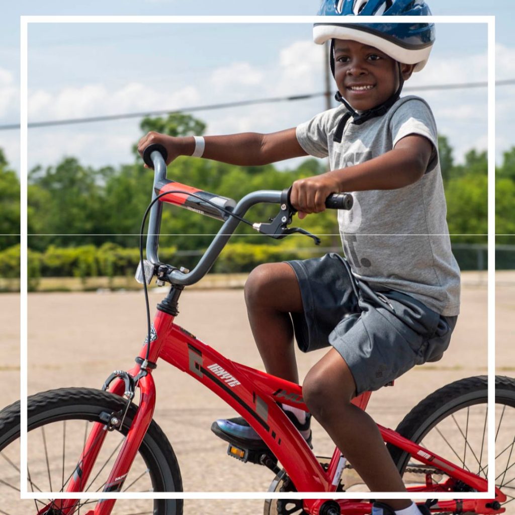 Black boy with blue helmet rides a red bicycle