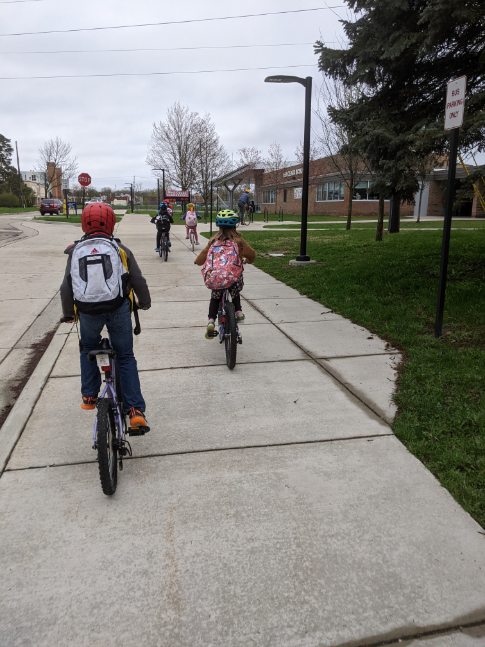 view of students, as part of a bike train, biking towards a school